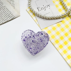 Macro view of heart-shaped phone grip with purple foil flakes in resin finish