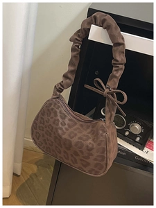 Détail d'un sac léopard avec bandoulière plissée et nœud sur fond de décor vintage