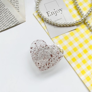 Detail of heart-shaped phone grip with rose gold foil flakes on plaid background