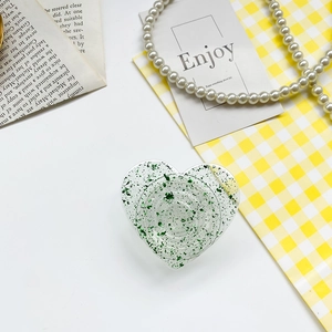 Detail of green glitter heart phone socket holder with gold foil on a minimalist desk