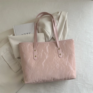 Pink minimalist tote bag with wrinkled patent leather texture and slim shoulder straps