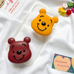 Close-up of transparent phone case featuring 3D cartoon bear socket stands on a white fabric