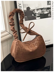 Détail d'un sac à bandoulière en daim marron avec bandoulière froncée et nœud décoratif