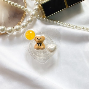 Detailed view of heart-shaped glitter phone grip with 3D bear on white silk background