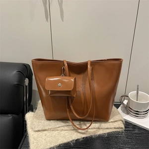 Retro brown glossy faux leather large tote bag with a small matching pouch on a soft rug