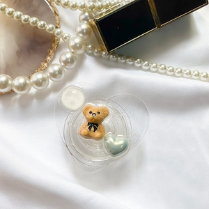 Detail of glittery heart phone grip with cute brown bear on white silk background