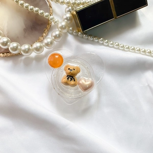 Detail of a transparent heart-shaped phone grip with 3D bear and pearl decorations