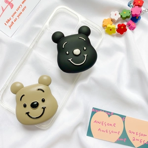 Detail of cute 3D bear-shaped phone grips in black and khaki on a clear phone case