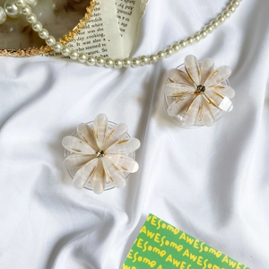 Detail of floral phone socket grip with white pearl finish and gold trim on silk