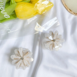 Detail of flower-shaped phone stand with white translucent petals and gold edges
