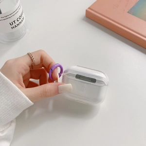 Gros plan d'une coque AirPods Pro transparente avec clip violet montrant une texture fine