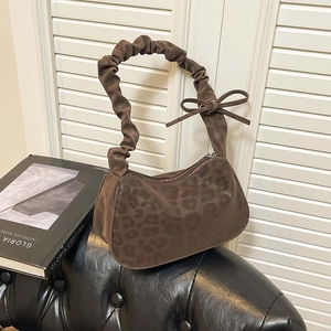 Sac bandoulière léopard marron avec poignée froncée et détail noeud sur chaise en cuir
