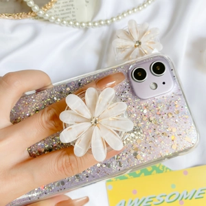 Detail of white daisy flower phone grip and sparkling purple glitter case on silk