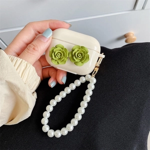 Detail of cream AirPods Pro case with green resin roses and white pearl wrist strap