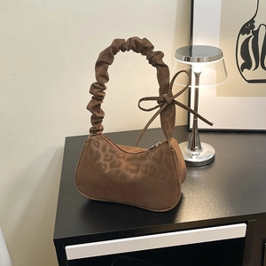 Sac bandoulière léopard chic avec poignée froncée et nœud sur une table en bois