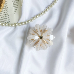 Close-up of translucent white flower phone grip with gold trim and center rhinestone