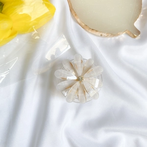 Detailed macro of a white resin flower phone grip with gold foil and crystal center