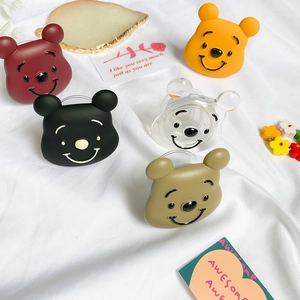 Cute cartoon bear collapsible phone grip stands in five colors on a white fabric background