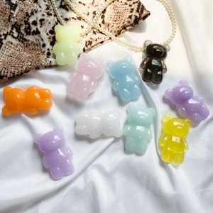 Close-up of colorful resin bear phone grips on a white silk background with pearls