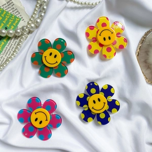 Detail shot of colorful flower phone grips with polka dots and smile face on fabric