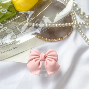 Matte pink ribbon bow expandable phone socket stand on silk background with pearls