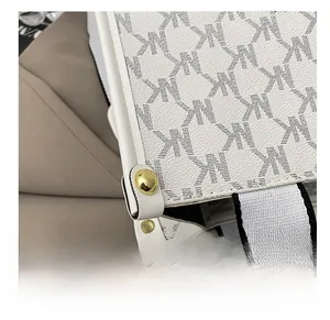 Close-up of white leather tote with MK monogram pattern and gold rivet accents