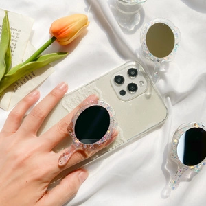 Macro view of a vintage hand-mirror phone grip with colorful glitters on white silk