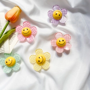 Detailed view of colorful checkered flower phone grips with a classic yellow smiley face