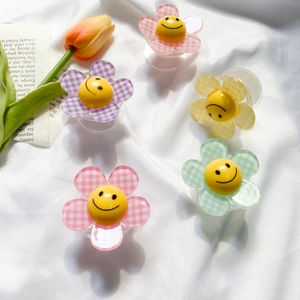 Detailed view of colorful checkered flower phone grips with smiling faces on white fabric