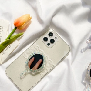 Close-up of phone case with vintage mirror stand, white lace, and colorful glitter sequins