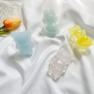 Close-up of four colorful 3D resin bear phone grips on white silk with yellow tulips
