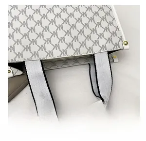Close-up of monogram pattern tote bag with contrast webbing handle and gold rivets