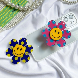 Detail of colorful floral phone grip sockets with smiley face on a phone case