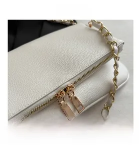 Close-up of white lychee leather texture and golden metal zipper detail on small bag