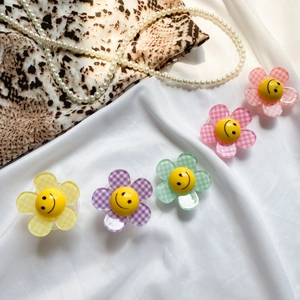 Detail of five colorful smiley flower phone grips on white silk with textured petals