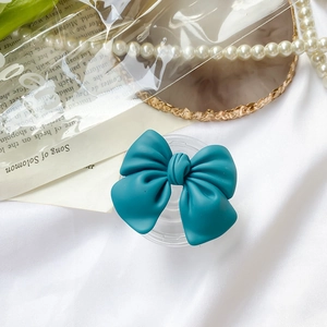 Teal bow-shaped Griptok with expandable transparent base on aesthetic silk background
