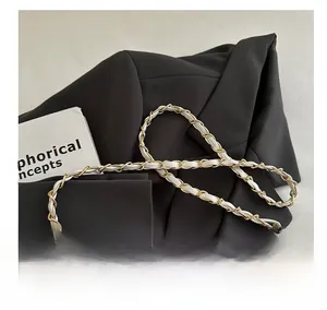 Detail of white lychee leather and gold metal chain strap on a luxury crossbody bag