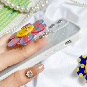 Detail shot of a colorful flower pop socket on a phone case with aesthetic white pearls