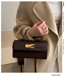 Detail of dark brown leather handbag featuring a polished gold twist lock closure and pebble texture
