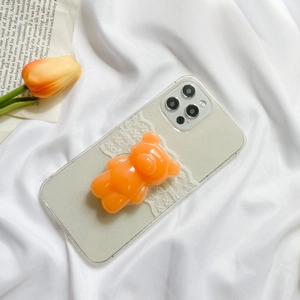 Detail of cute 3D orange bear phone socket on a transparent case with white lace and mint edges
