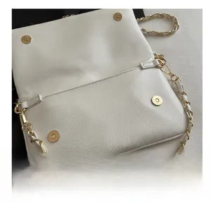 Close-up of white pebble leather handbag with gold magnetic snaps and chain strap