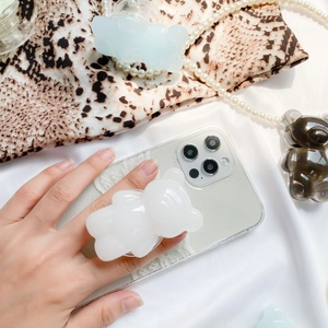 Detailed view of a white 3D bear phone grip on a glitter case held by a hand