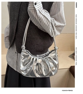 Dettaglio borsa a mezzaluna argento metallizzato con texture increspata e nodo sulla tracolla