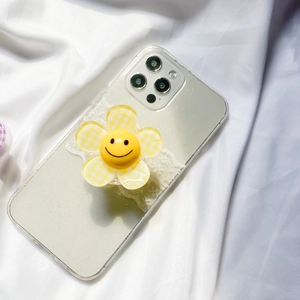 Detail of yellow checkered flower phone grip with smiley face on a clear case