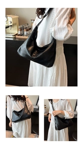 Détail du grand sac hobo noir en cuir brillant porté par un mannequin dans un café