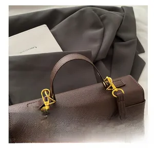 Detail of dark brown cross-grain leather handbag with golden turn-lock closure and sturdy handle