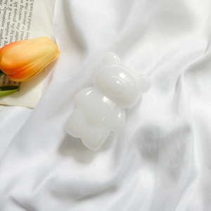 Close-up of a white 3D resin bear phone grip on elegant white silk fabric with flowers