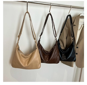 Détail de trois sacs demi-lune vintage en cuir en beige, marron et noir sur support