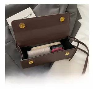 Detail view of large brown crossbody bag interior showing storage space for phone and makeup