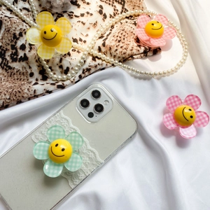 Close-up of three cute flower phone grips with checkered patterns and smiley faces